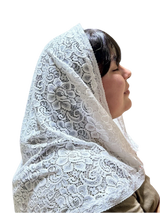 Person wearing a white lace headscarf in a store setting